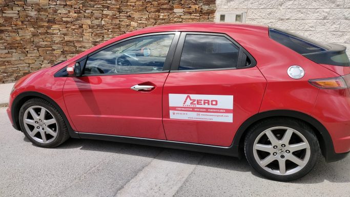 Coche rojo con logotipo y texto de una empresa en el lateral.