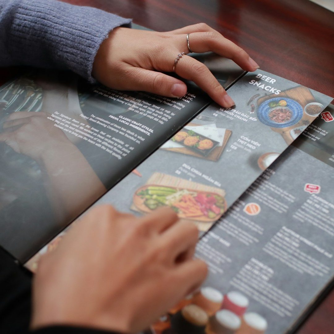 Manos revisando un menú de restaurante con diferentes platos y precios.