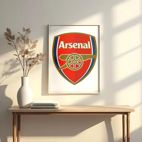 Logotipo del Arsenal en un marco, colocado sobre una mesa con un jarrón y un plato.