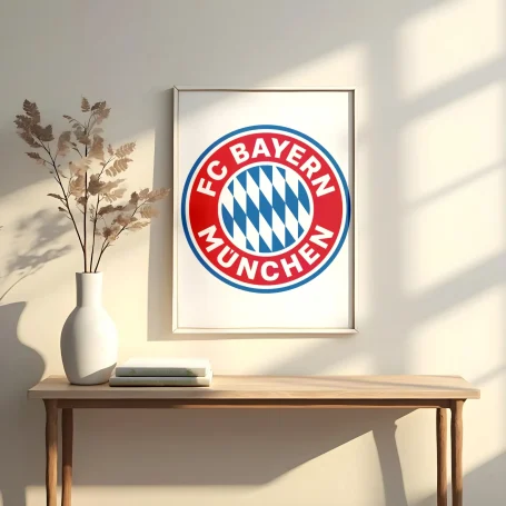 Logo del FC Bayern de Múnich en un marco sobre una mesa junto a un jarrón y ramas secas.