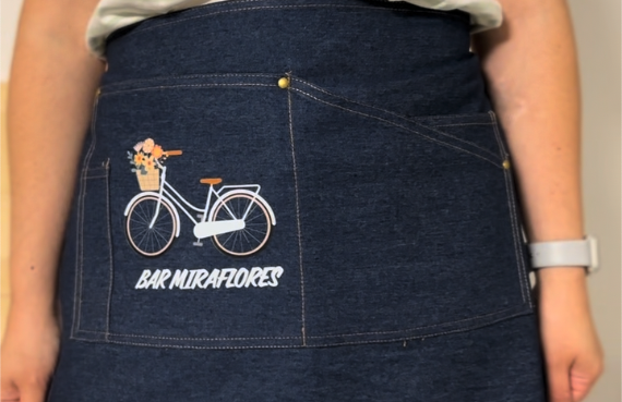 Delantal de mezclilla con un diseño de bicicleta y un perrito en el bolsillo.