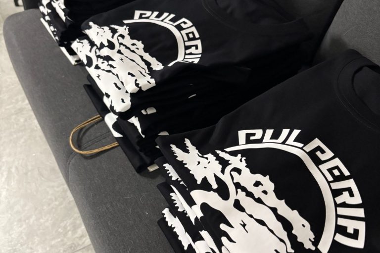 Camisas negras apiladas con un diseño gráfico blanco en la parte frontal.