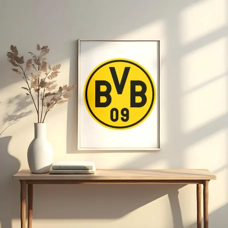 Logo de Borussia Dortmund (BVB 09) enmarcado, con un jarrón y plantas en la mesa.